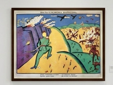 Framed artwork by K.S. Malevich's artwork 'Wilhelm Carousel' with a colorful landscape and figures on a white wall.