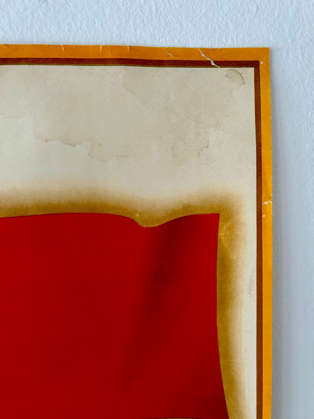 Framed artwork with a red center and wooden frame on a light blue wall.