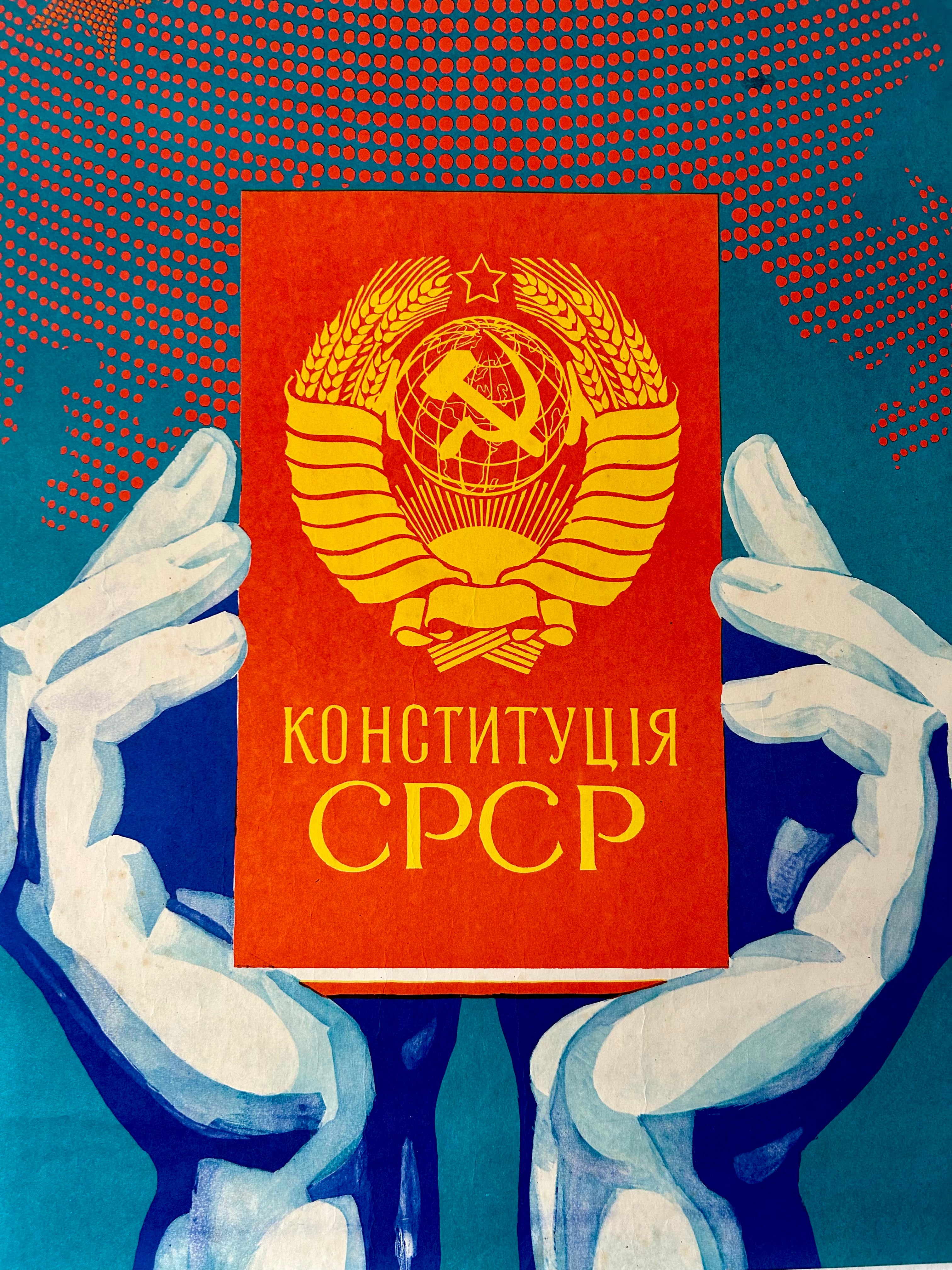 Book titled 'Конституція СРСР' held by stylized hands against a blue background with a red cover.