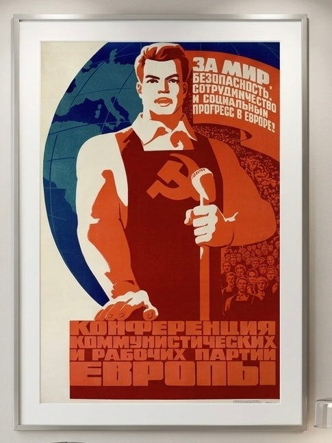 Vintage-style poster with a worker holding a hammer, framed on a wall.