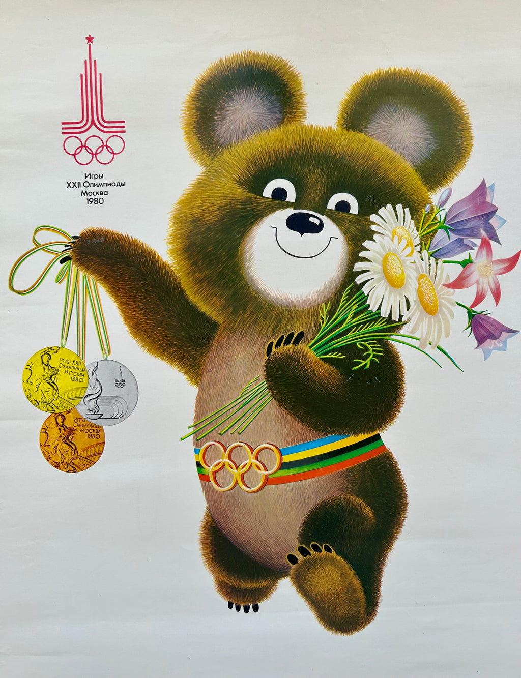 Illustration of Moscow Olympic bear holding flowers and medals with Olympic rings, on a light gray background.