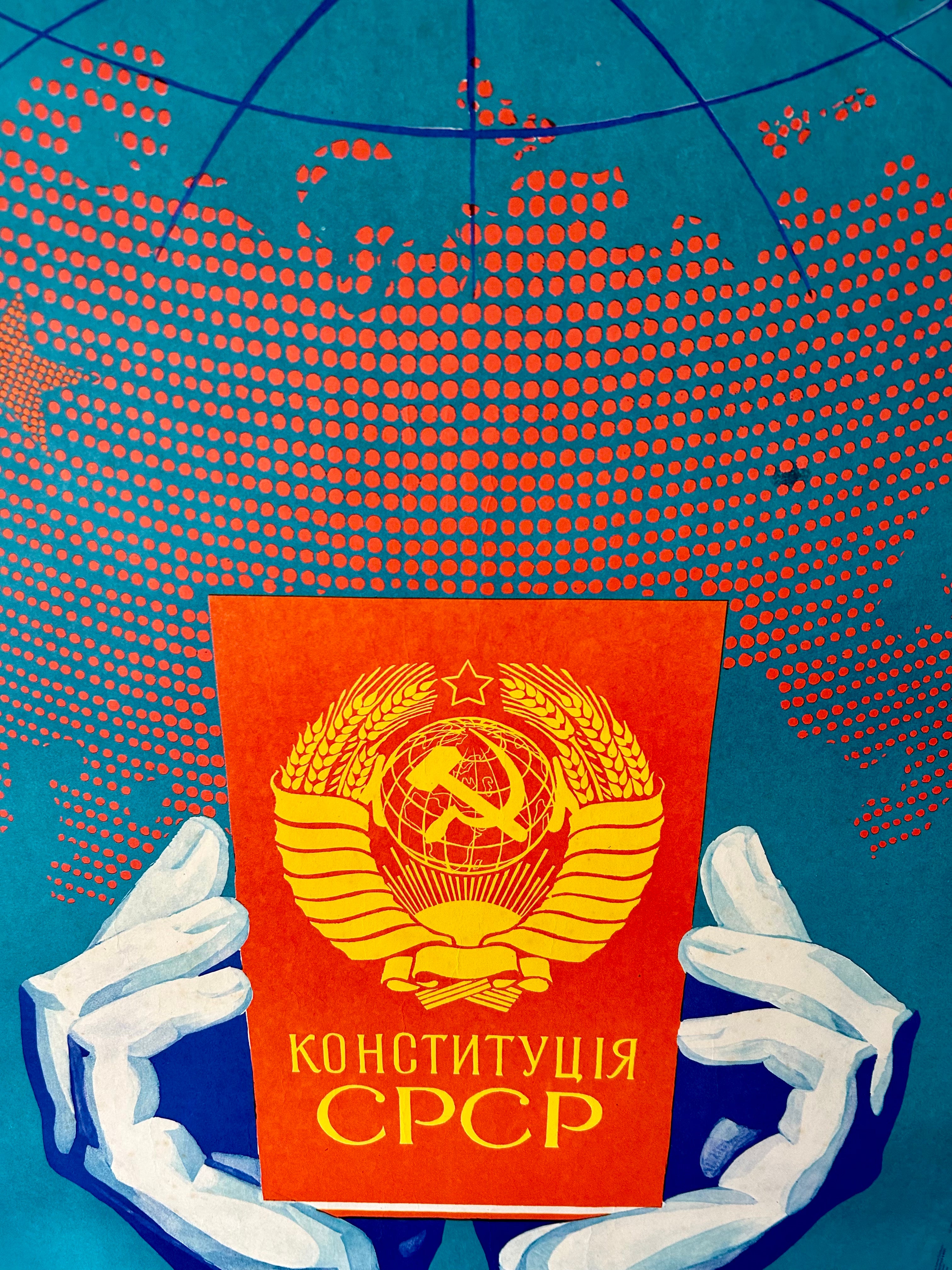 Book titled 'Конституция СССР' held by hands against a world map background