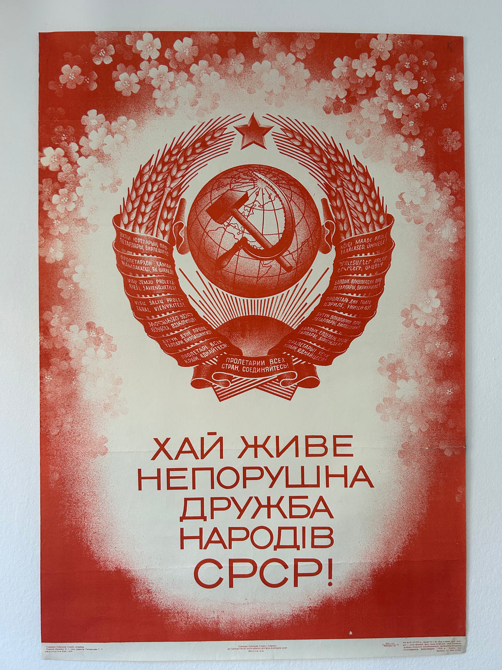 Soviet-era poster with emblem and text on a red background