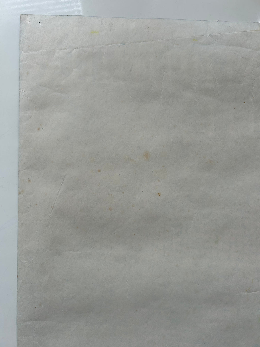 Sheet of beige paper with a small brown spot on a white background