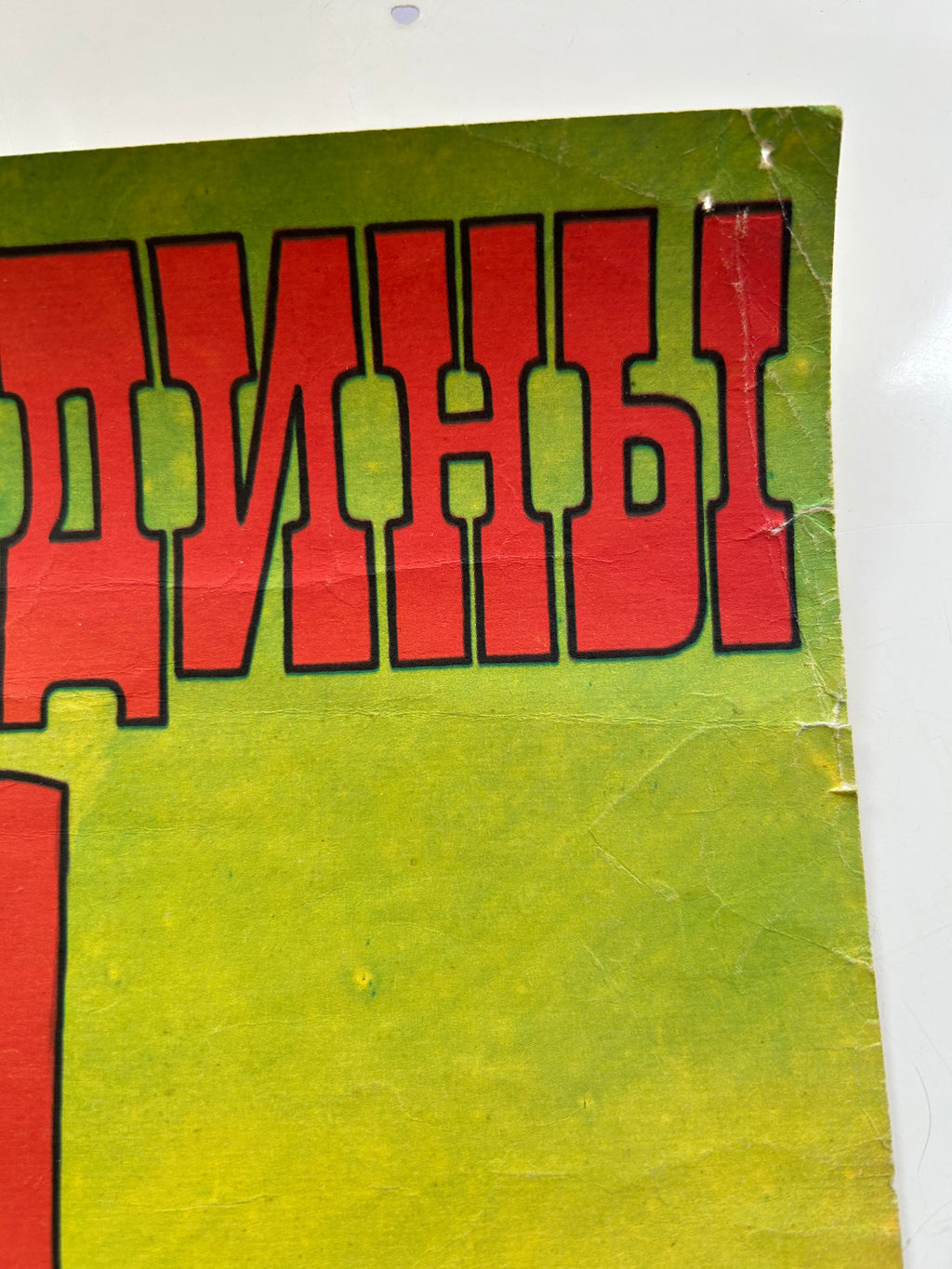 Close-up of a green and red sign with Cyrillic text on a white background